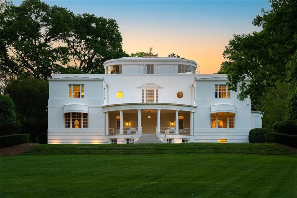 White historic Paces Ferry residence at dusk, with curved facades and a symmetrical columned terrace